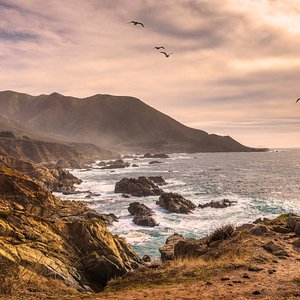 Scenic coastal view with rugged cliffs and ocean waves near caves.